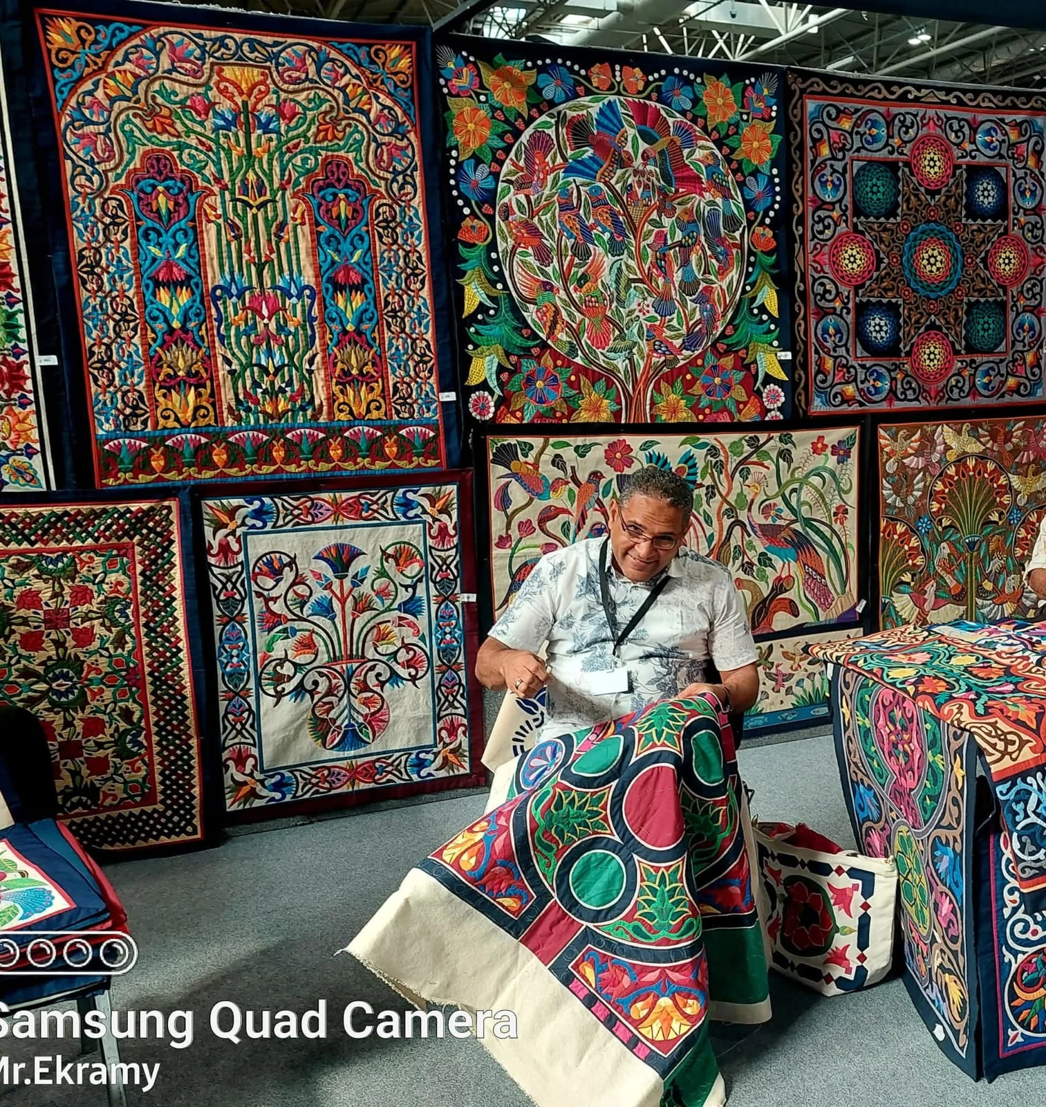 Master artisan Ekramy Al Farouk hand stitching colourful Khayamiya textiles, surrounded by richly patterned appliqué panels